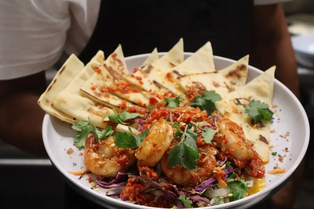 Chilli garlic prawns served on a board with charred flatbread
